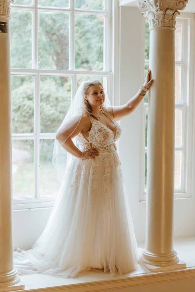 Bride in the window at Crowcombe Court during a summer wedding in Somerset, captured by a Crowcombe Court wedding photographer.