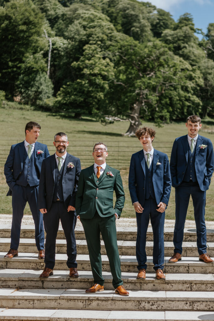 Grooms laughing at Crowcombe Court during a summer wedding in Somerset, captured by a Somerset Crowcombe Court wedding photographer