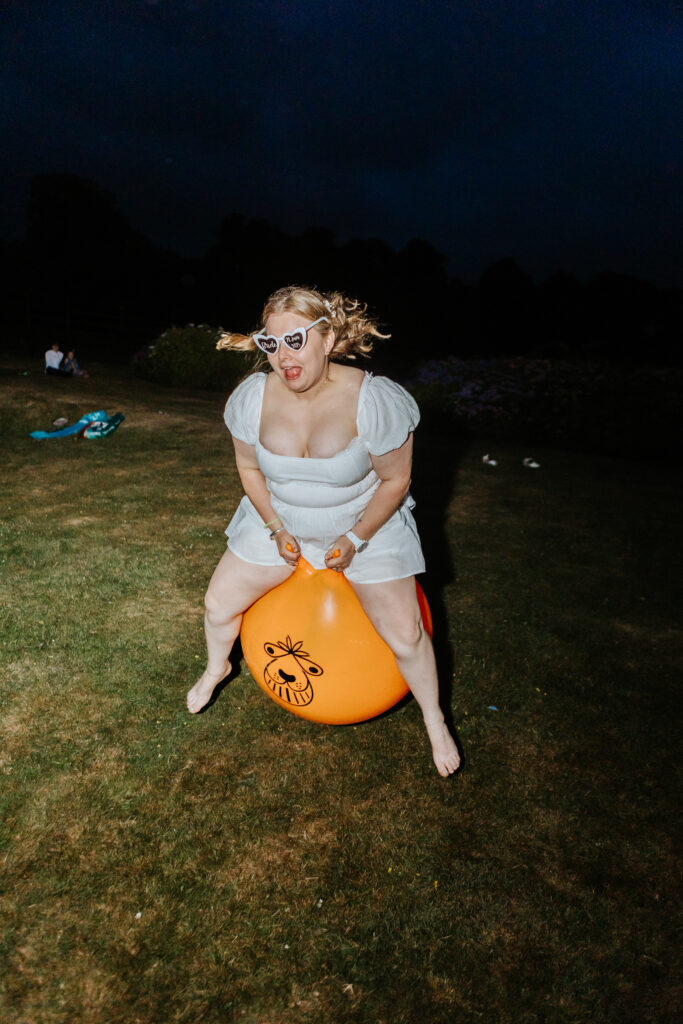 Bride on a space hopper at Crowcombe Court during a summer wedding in Somerset, captured by a Crowcombe Court wedding photographer.