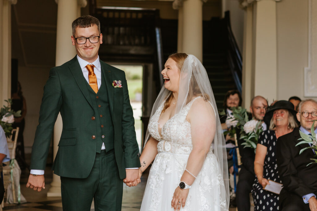 Bride and groom laughing in the great hall at Crowcombe Court during a summer wedding in Somerset, captured by a Crowcombe Court wedding photographer.