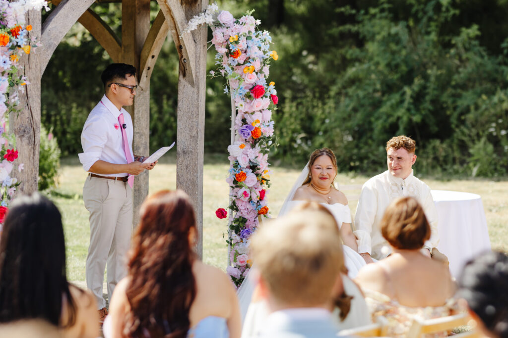 Wedding ceremony at Priston Mill near Bath with Bridgeton style vibrant floral arch